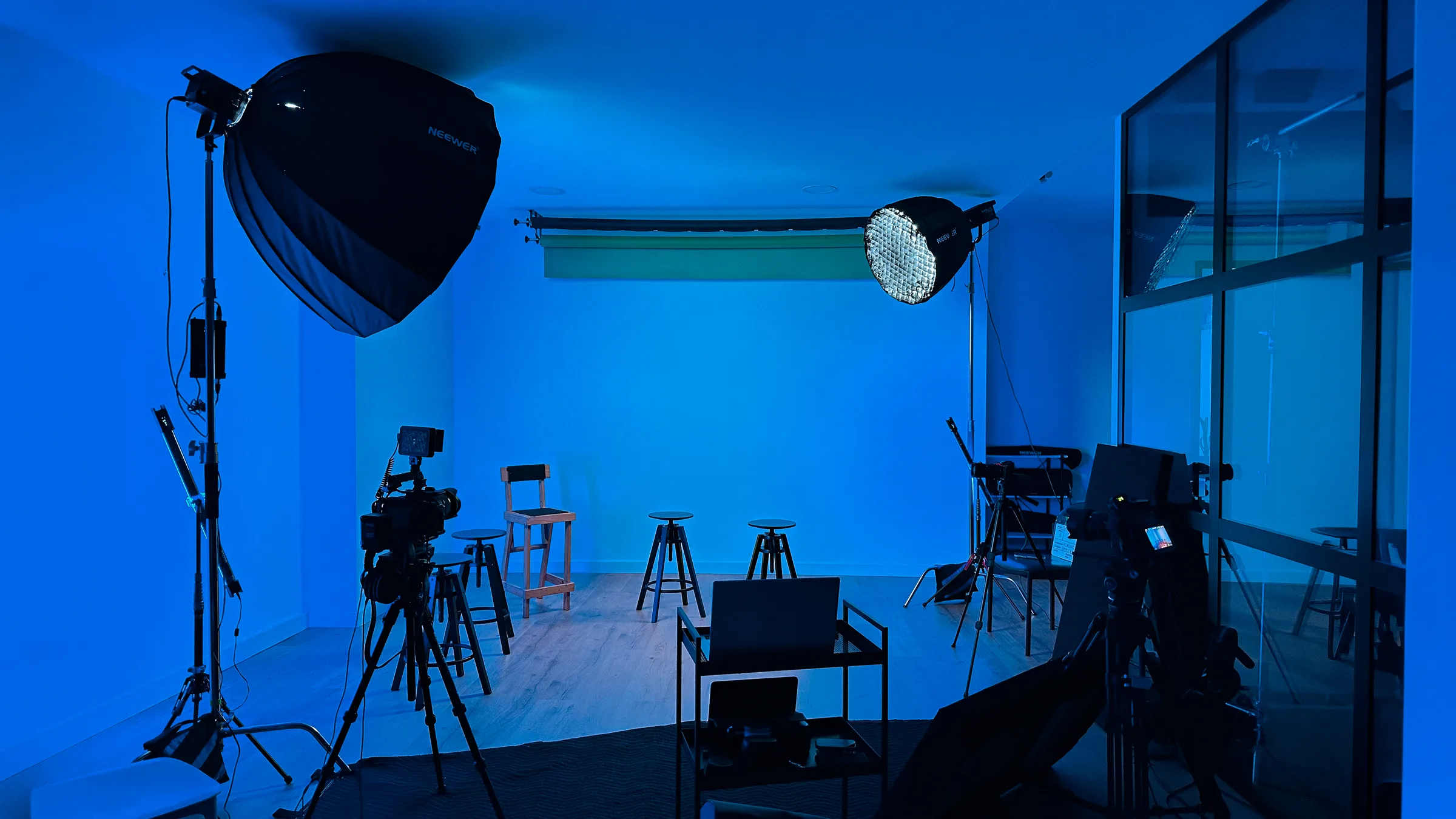 Setup de fotografia e vídeo no estúdio AIRLUSO: softbox Neewer, painel LED redondo, câmeras em tripé, ciclorama branco ao fundo.